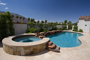 Taking a cue from the natural splendor of their Palm Springs location, this California homeowner accented the outer edge of their free-form swimming pool with a native stone wall, partnered with a spillover water feature and lush landscaping to draw the eye to the amazing mountain-lined horizon .