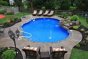 Thinking about building a pool for the summer? Get inspired by this freeform pool with a rounded natural stone deck and vibrant greenery.