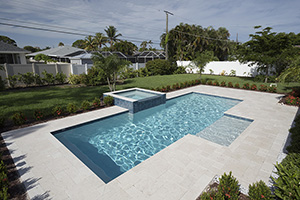 This pool area maximizes cool tones with NPT StoneScapes White finish, NPT Verona Borba Turquoise tile on the waterline and around the raised spa, and ivory travertine decking. Simplicity and beauty all in one.