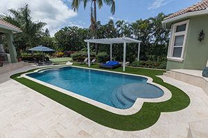 This luxurious Roman-shaped pool is finished in NPT's StoneScapes Tropics Blue Mini and outlined in elegant travertine coping. Cozy seating beneath a classic white pergola makes for a perfect place to take in the views.