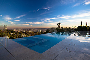 There’s no better spot for taking in the bright lights of the big city than a swimming pool nestled high in the hills. Ample travertine decking, an in-pool spa, vanishing edge, and illuminated dancing deck jets make this Los Angeles area home the ideal spot for evening entertaining.