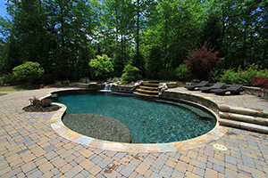 Dark pool finishes, like this StoneScapes Black aggregate finish, are more popular than ever. When combined with the trickling waterfall and local stone coping, the darker water color enhances the natural feel of this Georgia pool.