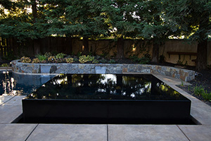 Dark as night and as smooth as ice, this sleek design is appealing to any eye. This pool features a raised hot tub with a vanishing edge.