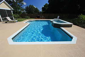 This inviting Florida pool utilizes contrasting elements; the white knockdown coping, dark NPT Verona Boticas Green 6" x 6" tile around the spa and waterline create a bold perimeter around the blue StoneScapes Aqua Cool Mini Pebble pool interior.