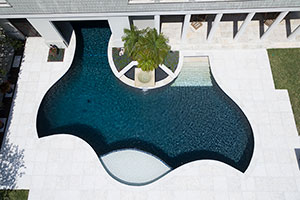 Get creative with your backyard design like this whale tail shaped pool! The two-tone finish of this lakeside pool includes glass beads that sparkle in the sun. The tanning ledge is finished in NPT's JewelScapes Crystal, which matches the deck and sets it apart from the StoneScapes Midnight Blue Touch of Glass pool interior.