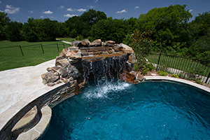 Give your pool a rocky touch with a built in waterfall and secluded grotto. This awesome pool area combines the elegance of travertine with the beauty of natural stone, perfectly unified by NPT's Catania Sand waterline tile.