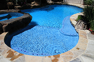 Give your pool finish a dash of color by adding peppbles to boarder your steps in. This cute addition stands out amongst this natural pool design and bright blue colored waters.