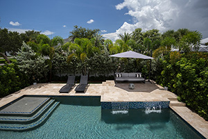 Shade umbrellas are a great addition for poolside lounging when you need a break from the sun. The raised corner of this travertine deck provides a nice view of the StoneScapes Tahoe Blue water below.