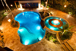 A custom raised spillover spa with interior fire pit cascades into the freeform pool below. Perfect for entertaining, pool lighting creates an exciting and adventurous feel and allows the homeowner to enjoy the pool after sunset.