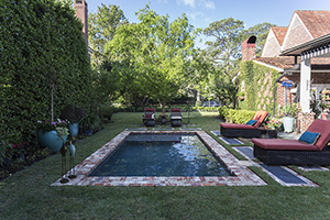 Thoughtful pool design should complement the structure and style of your home. This Florida homeowner carried the cozy cottage feel to their poolscape, using brick hardscape elements, natural turf decking, and a petite “party” pool to create an inviting and seamless flow between indoor and outdoor living.