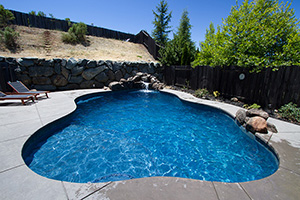 Radiant blue water emanates from every curve of this luxurious spool complete with a waterfall, jumping rock and stamped concrete deck. NPT's Silverstone Marine pool tile defines the waterline.