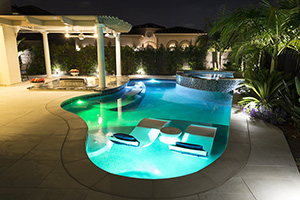 This homeowner made a small space into the perfect entertainment zone with raised spa, sunken outdoor kitchen, swim-up bar with bench seating and a shaded tanning ledge with two in-water loungers.