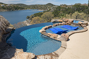 Let your worries drift away as you enjoy lounging in this fabulous spillover cliffside pool with lake view. NPT QuartzScapes Reflections Midnight Blue pool finish creates the rich watercolor.