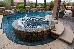 Golds, blues and browns in the NPT Jules Rustic Blue Blend spa tile selection mingle beautifully with the Bark Ledger Stone and QuartzScapes Midnight Blue pool finish. The color palette results in an energetic, adventurous poolscape.