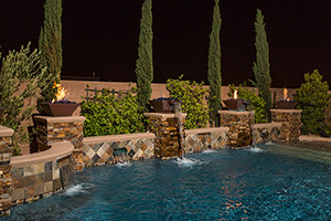 Prepare to be mesmerized by the open flames of these adventurous fire bowl columns created using NPT Bark Ledger Stone. NPT QuartzScapes Midnight Blue pool finish contrasts with warm stone.