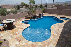 Pool features – like this backyard's rustic raised bond beam wall with fire bowls, in-pool seating area and large sun shelf with bubblers – create resort-worthy pool designs. Vibrant NPT QuartzScapes Tahoe Blue pool finish complements the Autumn Leaves Travertine coping and decking.