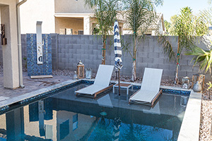 Define the atmosphere of your backyard with a color palette that reflects your style. This homeowner selected a nautical blue and white palette. A tiled shower and linen loungers enhance the at-the-beach feel.