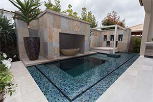 A true work of modern art, this pool features a custom tile shelf, large fire pit, and day bed under romantic in-set candles.