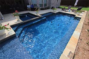 A true blue pool with a Barbados NPT pool finish, this geometric design features attractive angles on the steps and spa for a sleek, modern look.