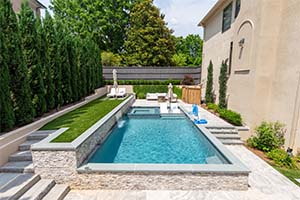 Elegant and cozy, this pool perfectly centers the stonework and landscaping in this Georgia home.  The dual ledge loungers look great againt the backdrop of a NPT French Gray finish.