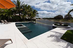 There's no limit to the beauty of an infinity edge pool. This design appears to seemlessly taper off into the Naples, FL water behind it with an NPT Midnight Blue pool finish.