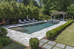 Square entry steps showcase how pool finishes appear differently depending on water depth. Perfect landscaping and a wooden pergola enhance the "Secret Garden" feel of this woodland pool.